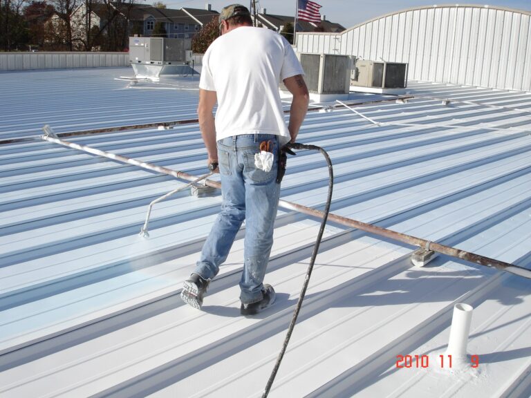 Man spray-coating a metal roof.